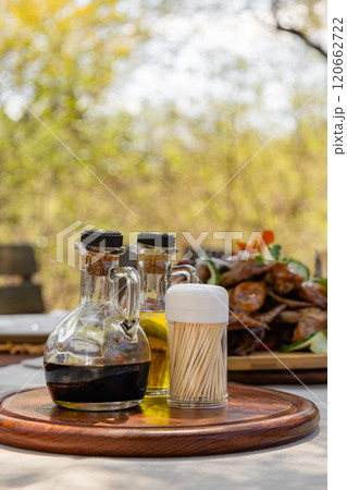 Two sauces in glass decanters and a jar of toothpicks on a wooden tray 120662722