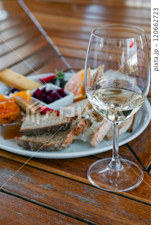 glass of white wine on a wooden slatted table and an appetizer 120662723