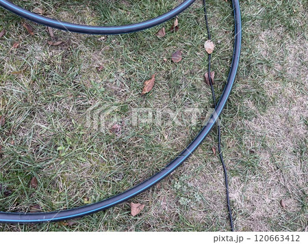 Garden hose laid out in vegetable garden rows 120663412