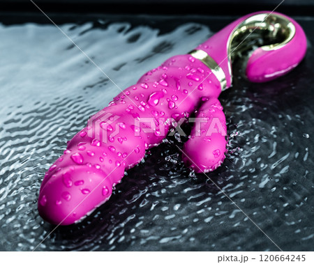 Pink ribbed vibrator in water. Circles on water around sex toy. Pink ribbed vibrator in water. Circles on water around sex toy. 120664245