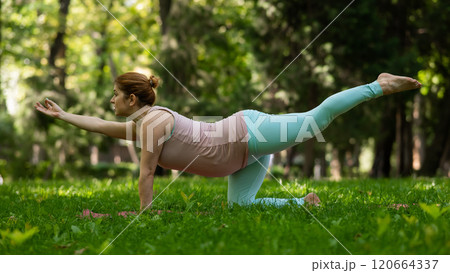 Pregnant caucasian woman doing yoga in the park.  120664337