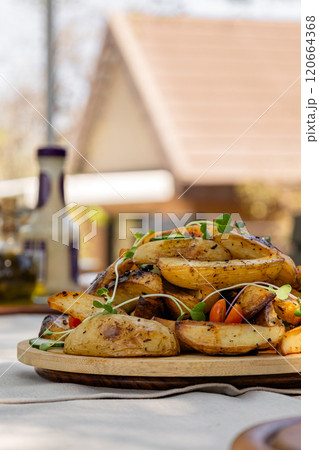 Crispy baked potato wedges garnished with microgreens on wooden plate 120664368