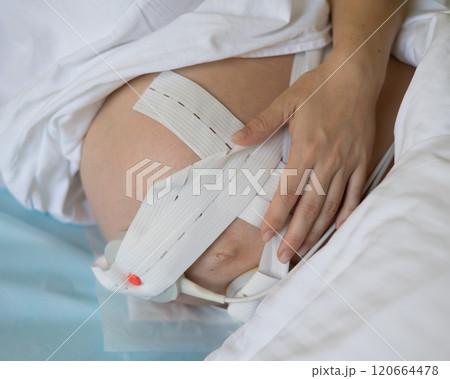 Close-up of pregnant woman's belly with Cardiotocography sensor in delivery room of maternity home. Close-up of pregnant woman's belly with Cardiotocography sensor in delivery room of maternity home. 120664478