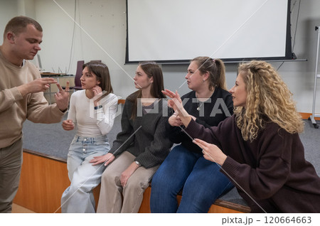 Young people communicate in sign language in a university classroom.  120664663