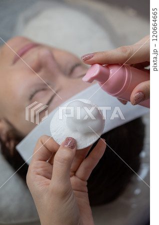 A professional applies cleansing foam to a cotton pad in a beauty salon. A professional applies cleansing foam to a cotton pad in a beauty salon. 120664665