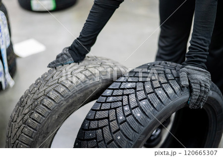 Mechanic keeps new summer and winter car tires in the garage. Comparison of wheels for different seasons. Mechanic keeps new summer and winter car tires in the garage. Comparison of wheels for different seasons. 120665307