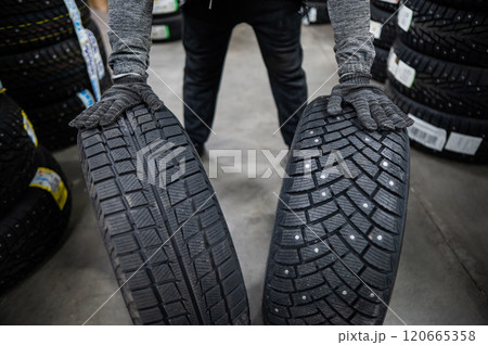 Mechanic keeps new summer and winter car tires in the garage. Comparison of wheels for different seasons. Mechanic keeps new summer and winter car tires in the garage. Comparison of wheels for different seasons. 120665358
