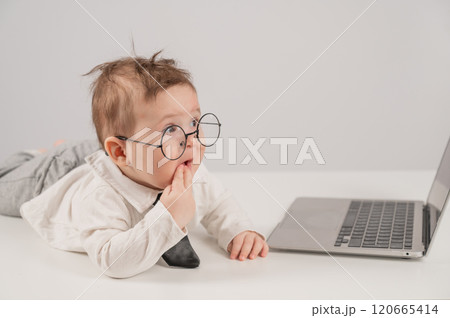 Cute baby in glasses and suit working on laptop. Cute baby in glasses and suit working on laptop. 120665414