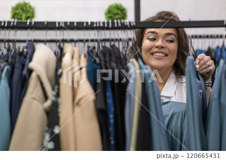 Portrait of a fat woman in a plus size store through hangers with clothes. Portrait of a fat woman in a plus size store through hangers with clothes. 120665431