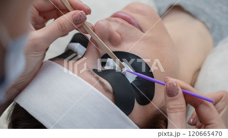 The master cleans the client's eyelashes from sebum before extensions.  120665470