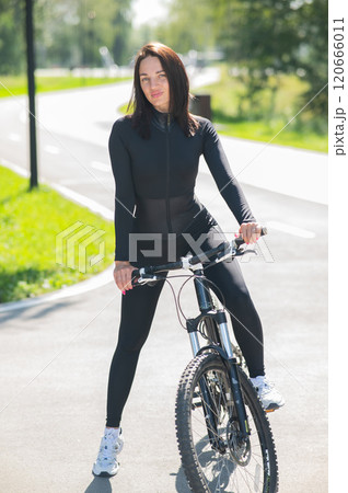 Caucasian woman riding a bike in a park. Vertical photo. Caucasian woman riding a bike in a park. Vertical photo. 120666011