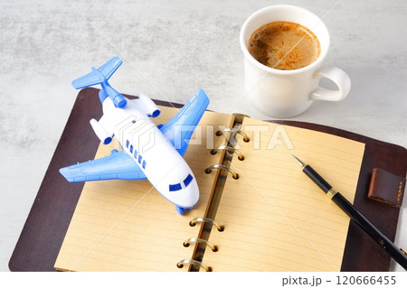 ミルク入りのコーヒー、カフェ・ラテと飛行機、リング式のシステム手帳で、旅行を計画しているイメージ ミルク入りのコーヒー、カフェ・ラテと飛行機、リング式のシステム手帳で、旅行を計画しているイメージ 120666455