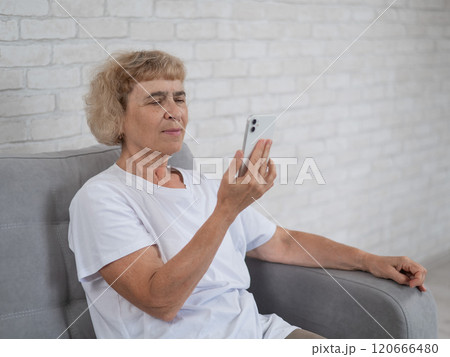 An elderly Caucasian woman suffers from myopia and tries to read a message on a smartphone. An elderly Caucasian woman suffers from myopia and tries to read a message on a smartphone. 120666480