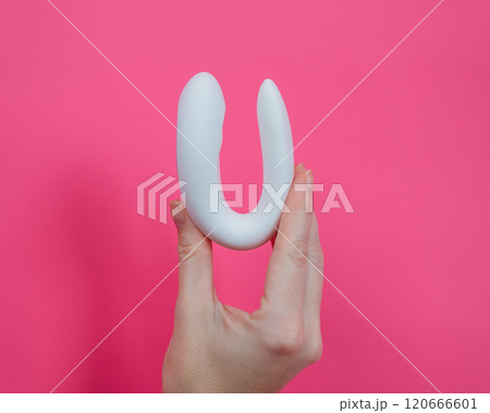 Woman holding white curved sex toy on pink background.  120666601