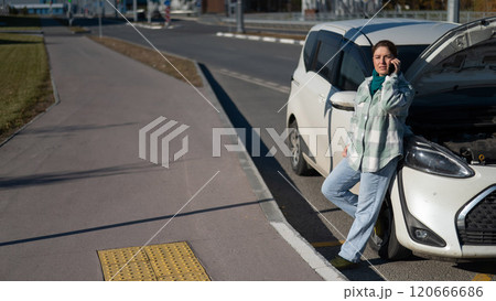 Sad Caucasian woman calling on phone while standing near car with open hood.  120666686