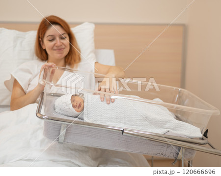 A young mother admires her newborn son in the maternity hospital.  120666696
