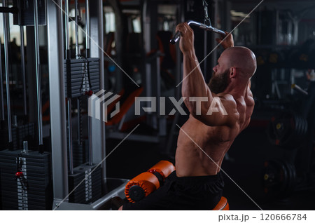 Caucasian man doing lat pull-downs on a machine. Caucasian man doing lat pull-downs on a machine. 120666784