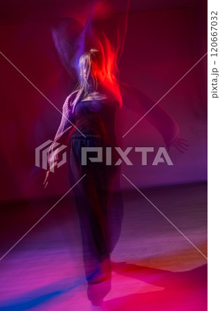 A young woman dances contemporary dances in blue and red light. Long exposure. Vertical photo.  120667032