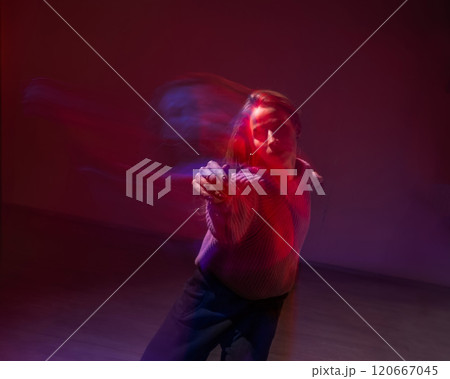 A young woman dances contemporary dances in blue and red light. Long exposure photo.  120667045