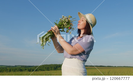 Holidays Weekend Adventure. Portrait - Countryside Woman Hold Flowers In Rural Nature. Magical Landscape With Wildflower Field, Travel And Spring Concept. Moves slowly. 120667777