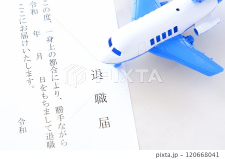 オフィスのデスクの上に置かれた退職届と飛行機で、これから会社を辞めて、自由に羽ばたくイメージ 120668041