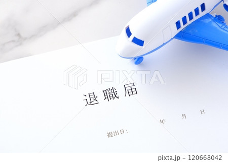 オフィスのデスクの上に置かれた退職届と飛行機で、これから会社を辞めて、自由に羽ばたくイメージ 120668042