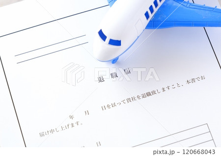 オフィスのデスクの上に置かれた退職届と飛行機で、これから会社を辞めて、自由に羽ばたくイメージ 120668043
