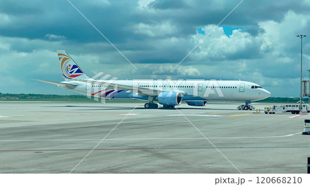Large passenger airliner is taxiing on the runway, preparing for takeoff or after landing, under a cloudy sky 120668210