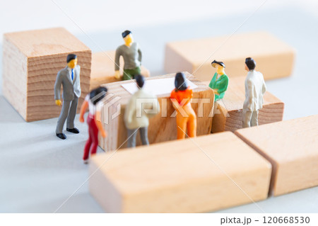 テーブルを囲んで話し合いをするミニチュアの人々 120668530