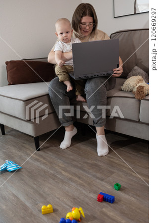 A Parent Juggling Working from Home while Comfortably Sitting with a Baby on Lap 120669297