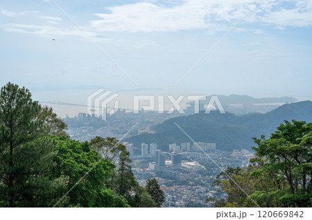 Stunning panoramic view of GeorgeTown Malaysia from hilltop, featuring lush green forest foreground, high-rise buildings, serene sea, cloudy sky, harmonious blend of urban and natural landscapes Stunning panoramic view of GeorgeTown Malaysia from hilltop, featuring lush green forest foreground, high-rise buildings, serene sea, cloudy sky, harmonious blend of urban and natural landscapes 120669842