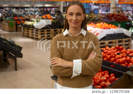 Woman standing confidently in grocery store with fresh produce on display Woman standing confidently in grocery store with fresh produce on display 120670166