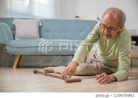 Sick senior old man falling down lying on floor because stumbled at home alone with wooden cane walking stick in living room, elderly man retired grandfather having accident after standing from sofa Sick senior old man falling down lying on floor because stumbled at home alone with wooden cane walking stick in living room, elderly man retired grandfather having accident after standing from sofa 120670961