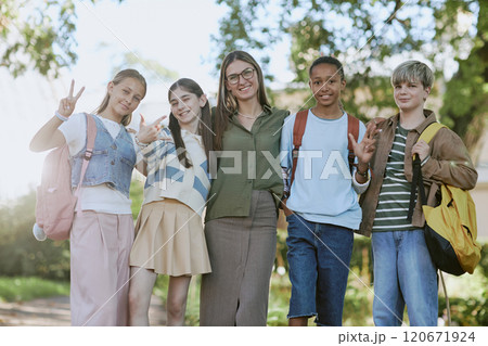 Low angle of cheerful young female tour guide and group of teen students posing for camera in botanical garden Low angle of cheerful young female tour guide and group of teen students posing for camera in botanical garden 120671924