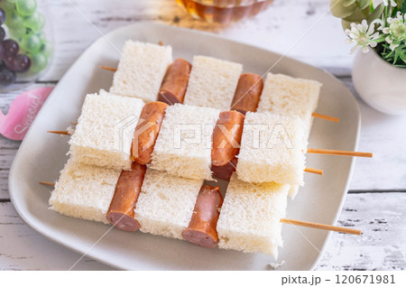 皿に盛った串に刺したパンとウインナー 120671981