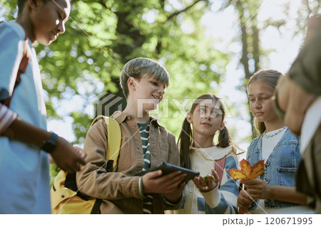 Low angle view of ethnically diverse teen boys and girls discussing plants during tour in botanical garden 120671995