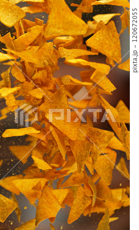 Freeze motion of flying fried tortilla nachos chips on gradient yellow background 120672055
