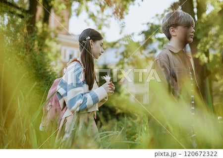 Side view medium shot of teen boy and girl walking along path in local botanical garden 120672322