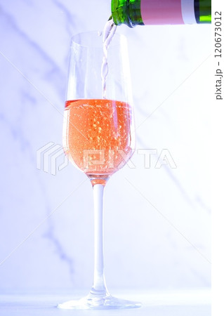 よく冷えたロゼのシャンパン（スパークリングワイン）をフルートグラスに注ぐ 120673012