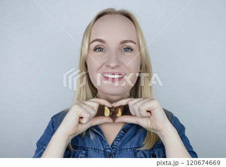 Prevention of thyroid disease. Woman holding a brazil nut in the shape of a thyroid gland. Nut rich in selenium Prevention of thyroid disease. Woman holding a brazil nut in the shape of a thyroid gland. Nut rich in selenium 120674669