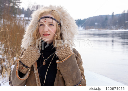A young woman with blonde hair dressed in a warm fur-lined leather coat A young woman with blonde hair dressed in a warm fur-lined leather coat 120675053