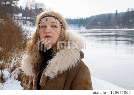 A young woman with blonde hair dressed in a warm fur-lined leather coat 120675066