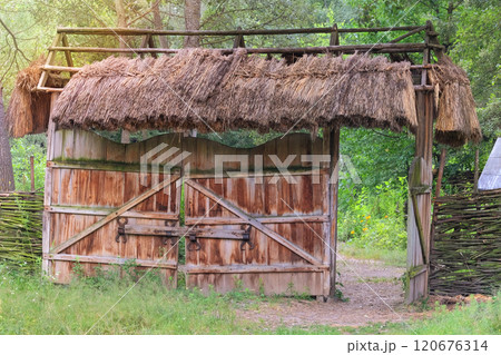 Aged wooden gate in countryside. Traditional wooden farmhouse. Village ethnographic gates. Vintage exterior. Sunny day. Aged wooden gate in countryside. Traditional wooden farmhouse. Village ethnographic gates. Vintage exterior. Sunny day. 120676314