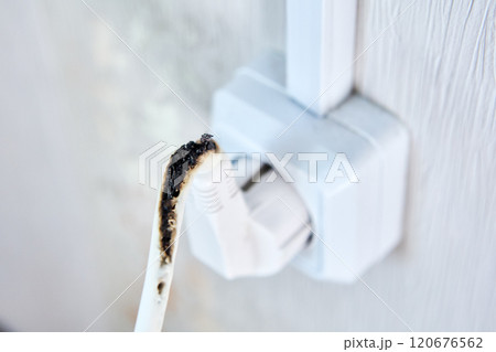 An electrical plug with burnt wire in socket. 120676562