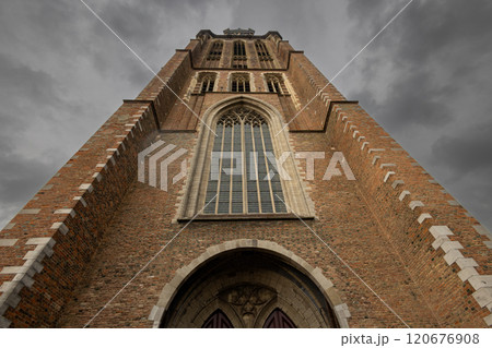 A majestic Gothic church under a dramatic cloudy sky. The intricate brickwork, towering windows, and clock tower reflect its historic architecture and timeless grandeur. A majestic Gothic church under a dramatic cloudy sky. The intricate brickwork, towering windows, and clock tower reflect its historic architecture and timeless grandeur. 120676908