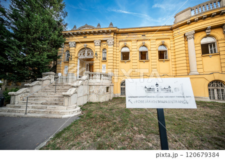 Budapest, Hungary. August 27, 2022. Shot at the main entrance of the Szechenyi Baths, the largest in the city. An information sign points to it. Travel destinations, beautiful summer day. 120679384