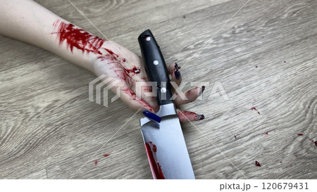 Close up photo of girl bloody hand with bloody knife on floor. Traces of blood in crime scene with knife. Murder of girl and murder weapon on floor of apartment 120679431