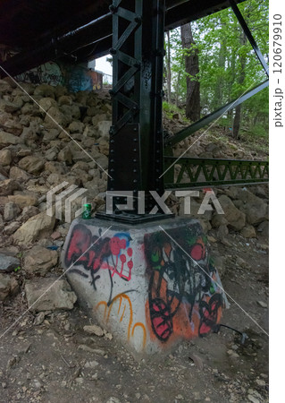 Colorful Graffiti on Concrete Support of Metal Bridge in Forested Area. 120679910