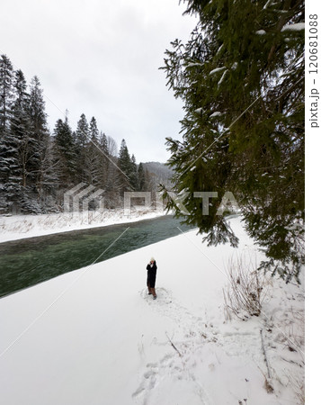 Person on Snowy Riverbank with Forest and Bridge Person on Snowy Riverbank with Forest and Bridge 120681088