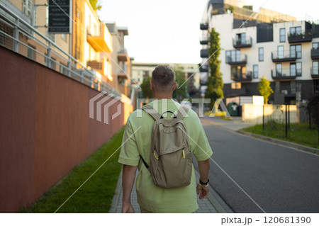 Back view of Caucasian man with blonde hair and backpack walking on street of Krakow city Back view of Caucasian man with blonde hair and backpack walking on street of Krakow city 120681390